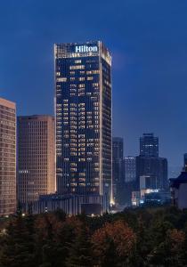 Un palazzo alto in una città di notte di Hilton Chongqing Liangjiang New Area a Chongqing