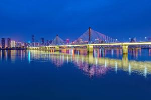 eine Brücke über einen Wasserkörper in der Nacht in der Unterkunft Hilton Changsha Riverside in Changsha