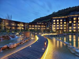 Hilton Jiuzhaigou Resort في جيوتشايقو: مبنى امام مبنى به نهر