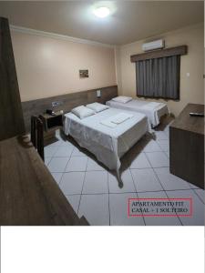 ein Hotelzimmer mit 2 Betten und einem Tisch in der Unterkunft HOTEL CAMPO GRANDE in Campo Grande