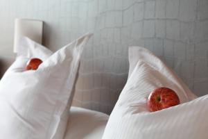 dos manzanas están sentadas sobre almohadas en una cama en The Seven Hotel, en Esch-sur-Alzette