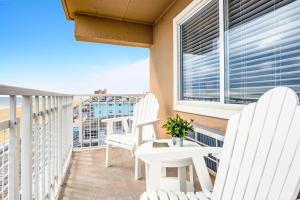 uma varanda com cadeiras brancas, uma mesa e uma janela em Dunes Suites Oceanfront em Ocean City