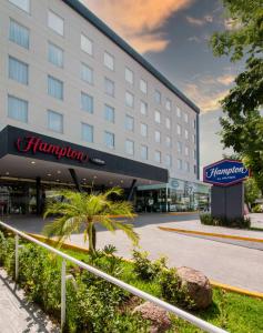 budynek hotelowy z palmą przed nim w obiekcie Hampton by Hilton Aguascalientes Downtown w mieście Aguascalientes