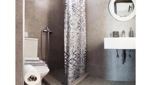 a bathroom with a shower curtain and a toilet and a sink at Studios Thea Fresh Rooms Thassos in Limenas