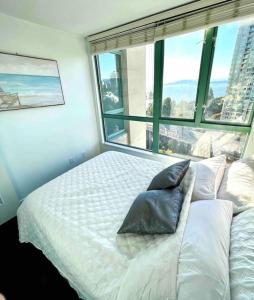 una camera da letto con un letto bianco e una grande finestra di Stunning ocean (sound of waves) a Vancouver