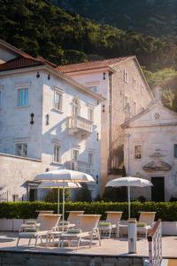 een groep stoelen en parasols voor een gebouw bij Heritage Grand Perast By Rixos in Perast