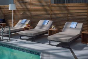 3 chaises longues à côté d'une piscine dans l'établissement Hilton Boston-Woburn, à Woburn