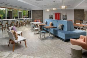 シャーロッツヴィルにあるHome2 Suites By Hilton Charlottesville Downtownのロビー(青いソファ、テーブル、椅子付)