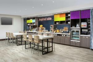 シャーロッツヴィルにあるHome2 Suites By Hilton Charlottesville Downtownのレストランのテーブルと椅子付きのキッチン