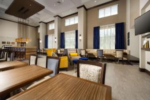 Hampton Inn & Suites Falls Church في فولز تشيرش: غرفة طعام مع طاولات وكراسي ونوافذ