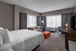 een hotelkamer met een bed, een stoel en een bureau bij Hampton Inn Boston Woburn in Woburn