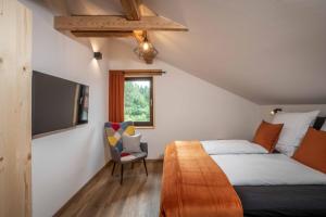 - une chambre avec un lit, une télévision et une chaise dans l'établissement Ski-Bike-Apartment Bayerwald, à Lohberg