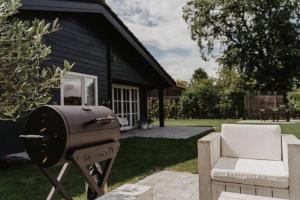 a grill and a chair in front of a house at Life & Cooking Holiday Home in Ermelo