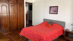 a bedroom with a bed with a red comforter at Habitaciones Frente Club Tenis in Cochabamba