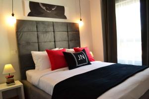 een slaapkamer met een groot bed met rode en zwarte kussens bij JN Boutique Apartments in Boekarest