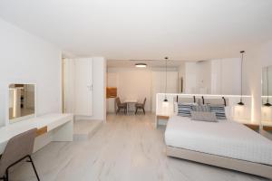 a white bedroom with a bed and a table at Arcs Suites & Residences in Mýkonos City