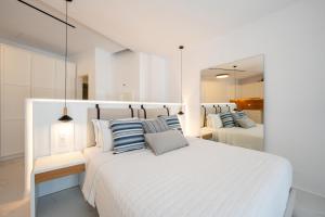 a white bedroom with two beds and two mirrors at Arcs Suites & Residences in Mýkonos City