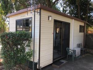 a small house with a chair in front of it at Batemans Bay Holiday Park & Hostel in Batemans Bay