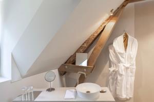 a bathroom with a white robe hanging under a stairs at Château du Pont d'Oye in Habay-la-Neuve