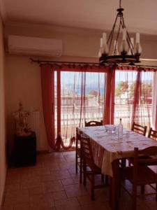 une salle à manger avec une table et une grande fenêtre dans l'établissement Κορινθιακός, à Corinthe