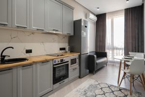 a kitchen with white cabinets and a table with a chair at Апартаменты бизнес-класса в ЖК 4YOU in Almaty