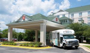 un bus blanc garé devant un bâtiment dans l'établissement Hilton Garden Inn BWI Airport, à Linthicum