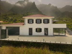 une maison blanche avec des montagnes en arrière-plan dans l'établissement Casa Avô da Pedra, By OP, à São Vicente