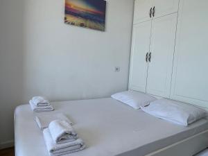 - une chambre blanche avec un lit et des serviettes dans l'établissement Arteg Apartments - Full Sea View, à Durrës