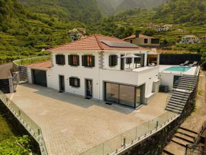 une grande maison blanche avec une piscine et des montagnes dans l'établissement Casa Avô da Pedra, By OP, à São Vicente