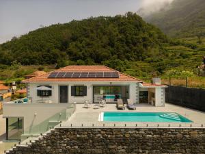 une maison avec une piscine en face d'une montagne dans l'établissement Casa Avô da Pedra, By OP, à São Vicente