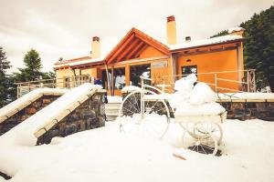 dom pokryty śniegiem z rowerem przed nim w obiekcie Natura Hotel Vytina w mieście Vytina