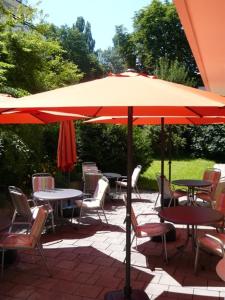 a patio with tables and chairs under an umbrella at Hotel Biederstein am Englischen Garten in Munich