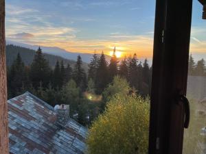 einen Blick auf den Sonnenuntergang von einem Fenster eines Hauses in der Unterkunft Pensiunea Joe Paltinis in Păltiniş