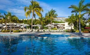 una piscina con palme e un resort di Grand Bliss Nuevo Vallarta a Nuevo Vallarta