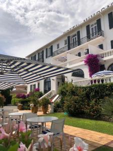 een binnenplaats met tafels en stoelen en een gebouw bij Hotel des Mimosas in Juan-les-Pins