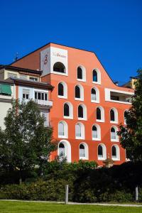 a large orange building with trees in front of it at Hotel La Briosa in Bolzano