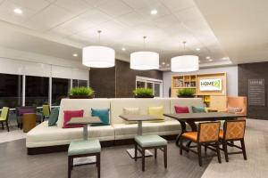 um átrio com um sofá, mesas e cadeiras em Home2 Suites by Hilton Houston Stafford - Sugar Land em Stafford