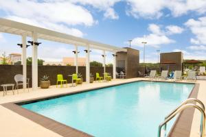 uma piscina num hotel com cadeiras e mesas em Home2 Suites by Hilton Houston Stafford - Sugar Land em Stafford