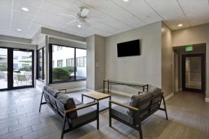 Homewood Suites by Hilton Indianapolis Carmel في كارميل: غرفة انتظار مع كنب وطاولة وتلفزيون