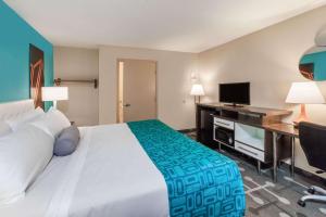 um quarto de hotel com uma cama, uma secretária e uma televisão em Howard Johnson by Wyndham Romulus Detroit Metro Airport em Romulus