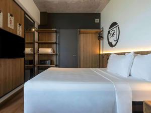 a bedroom with a large white bed and a television at ibis Styles Maceió Pajuçara in Maceió