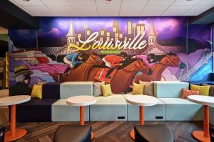 Mural ścienny w restauracji ze stołami i stołami w obiekcie Tru By Hilton Louisville Airport w mieście Louisville