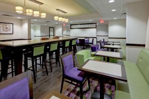 Hampton Inn Dumfries/Quantico في دومفريس: مطعم به كراسي وطاولات أرجوانية وأخضر