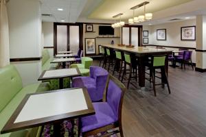 Hampton Inn Dumfries/Quantico في دومفريس: مطعم به كراسي وطاولات أرجوانية وأخضر