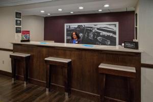 Hampton Inn Dumfries/Quantico في دومفريس: امرأة تقف خلف بار في مستشفى