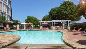 een zwembad met stoelen en tafels en een gebouw bij Hilton Austin Airport in Austin