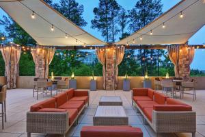 een patio met banken, tafels en verlichting bij Embassy Suites by Hilton Raleigh Durham Airport Brier Creek in Raleigh