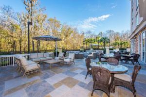 un patio con sillas, mesas y una sombrilla en DoubleTree by Hilton North Charleston - Convention Center, en Charleston