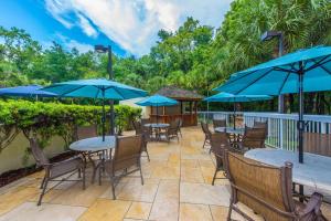 un patio con mesas y sillas y sombrillas azules en DoubleTree by Hilton North Charleston - Convention Center, en Charleston