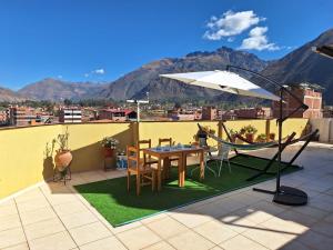 une table, des chaises et un parasol sur le toit dans l'établissement Chaska valle Inn, à Urubamba